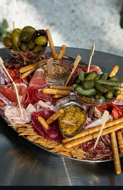 Fuente de picada con fiambres, pepinillos, aceitunas, grisines y salsas.